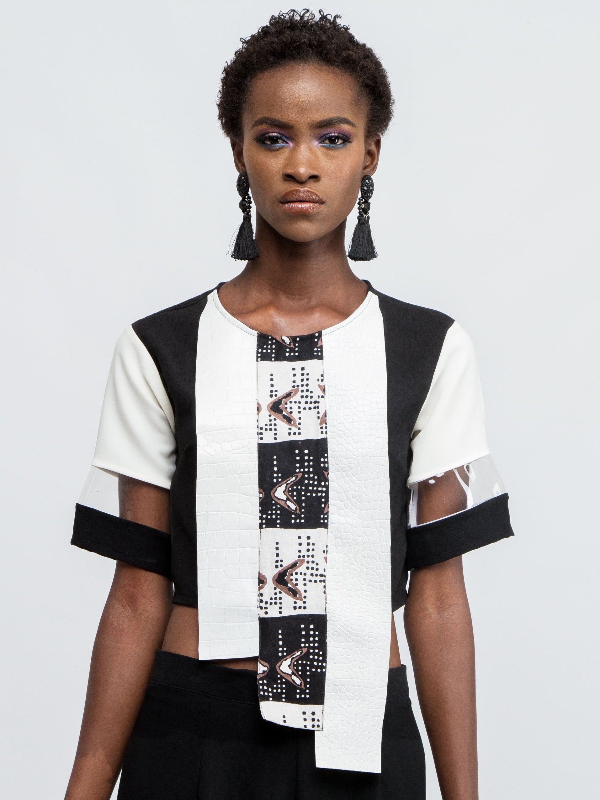Black asymmetrical crop top with textured leather look panels, print details and plexi detailed sleeves.  