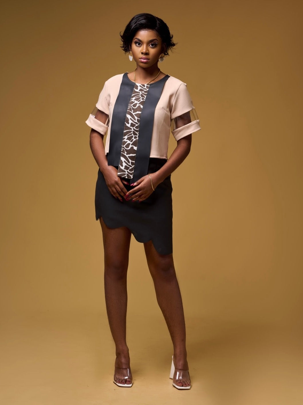 Light brown asymmetrical crop top with textured faux leather panels and plexi detailed sleeves.
